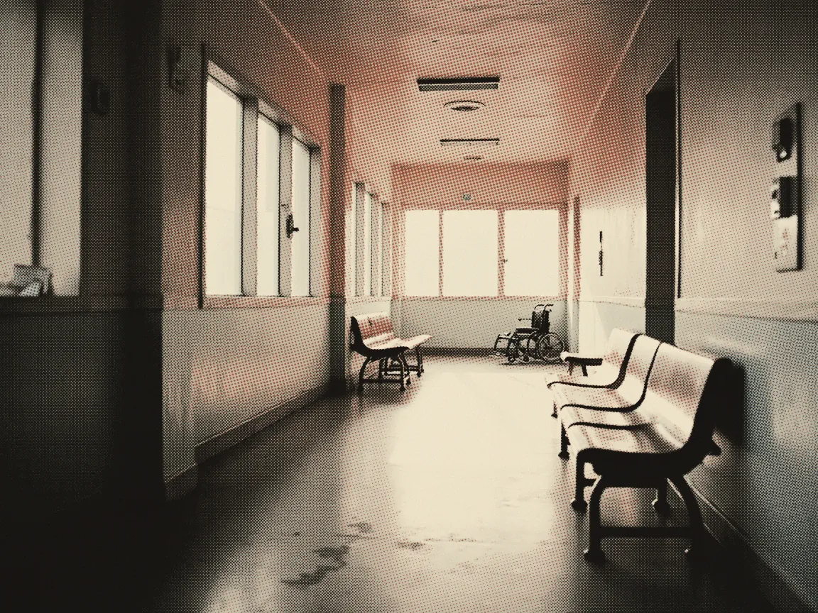Government vs Private Hospital Malaysia: Cost & Waiting Time — a hospital corridor with empty seats and a wheelchair at the far end